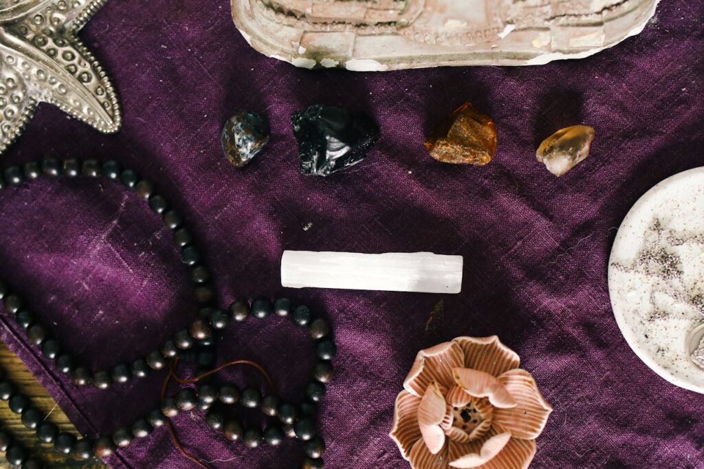 A still life featuring crystals, beads, and accessories on a purple fabric.